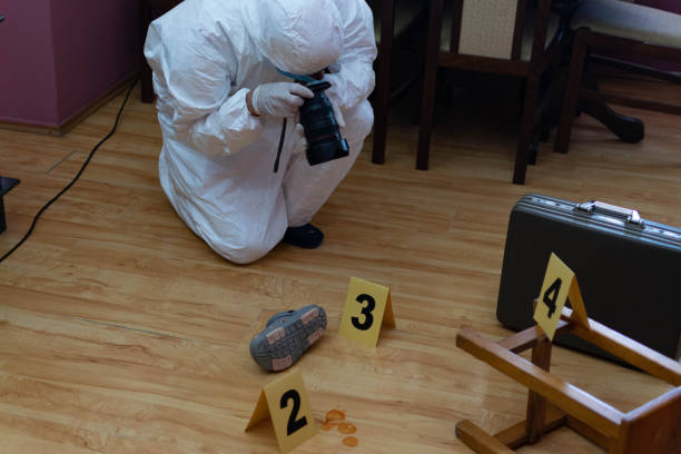 istock Forensic scientist, looking for the evidence on the crime scene, collecting fingerprints, photographing evidence, with his full protective suit, gloves, and forensic gear. 1323159899