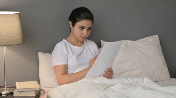 istock Young Indian Woman doing Paper Work in Bed 1323160601