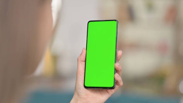 istock Woman Using Smartphone with Green Screen, Chroma Screen 1323161928