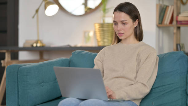 istock Beautiful Young Woman using Laptop on Sofa 1323161929