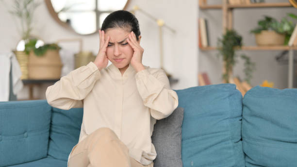 istock Young Indian Woman with Headache on Sofa 1323161987
