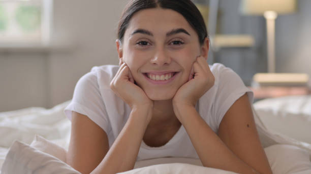 istock Latin Woman Laying in Bed Smiling at Camera 1323162381