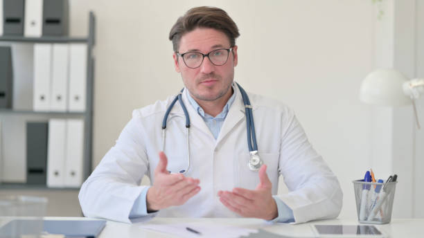 istock Middle Aged Male Doctor Talking on Video Call 1323163178