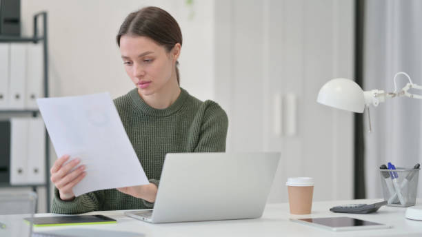istock Paperwork by Young Woman with Laptop and Documents 1323163318