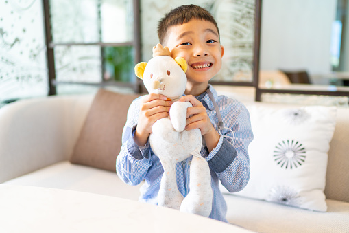 Happy boy with his favorite bear doll, smiling and looking at camera