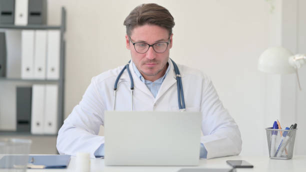 istock Middle Aged Male Doctor Working on Laptop 1323163329