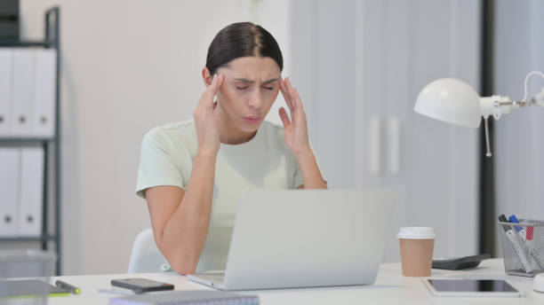 istock Young Latin Woman with Laptop having Headache 1323163780