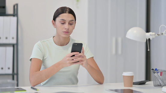 Young Latin Woman using Smartphone at Work