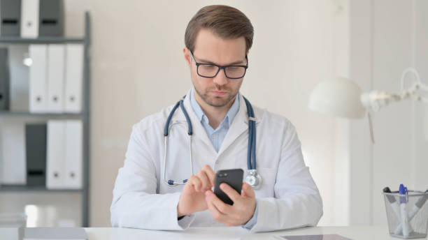 istock Male Doctor using Smartphone in Office 1323164623
