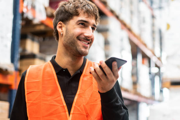 warehouse worker using mobile phone at work - conference phone imagens e fotografias de stock