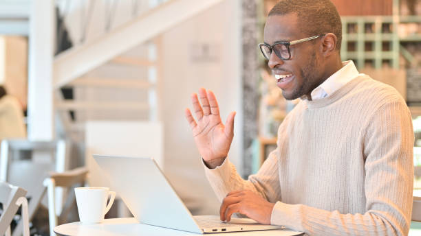 istock Cheerful African Man Talking on Video Call on Laptop in Cafe 1323166150