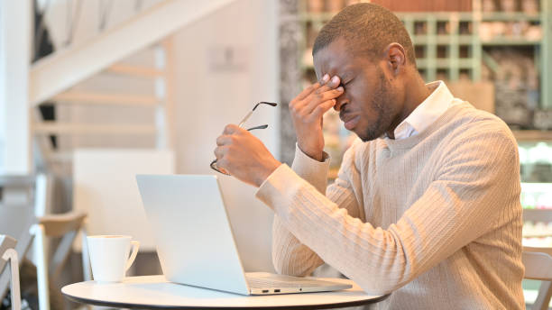 istock Stressed African Man with Laptop having Headache in Cafe 1323166155