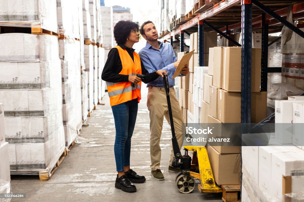 Worker following instructions of foreman at warehouse Worker following instructions of foreman at warehouse. Employee and supervisor are seraching boxes to dleivery on storage rack in warehouse. Warehouse Stock Photo