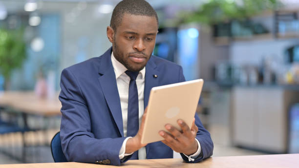 istock Serious African Businessman using Tablet in Office 1323166295