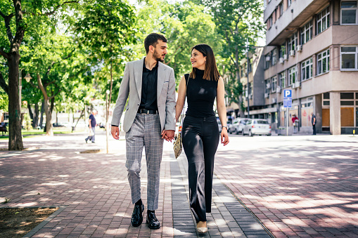Young cheerful couple walking in the city, holding hands