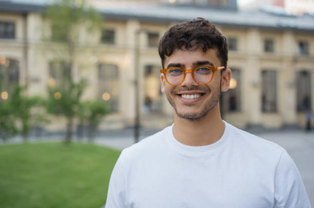 Young successful Indian man wearing stylish eyeglasses, standing on the street. Handsome asian model posing for pictures, looking at camera, smiling Authentic portrait of young successful Indian man wearing stylish eyeglasses, standing on the street. Handsome asian model posing for pictures, looking at camera, smiling 20 24 years stock pictures, royalty-free photos & images