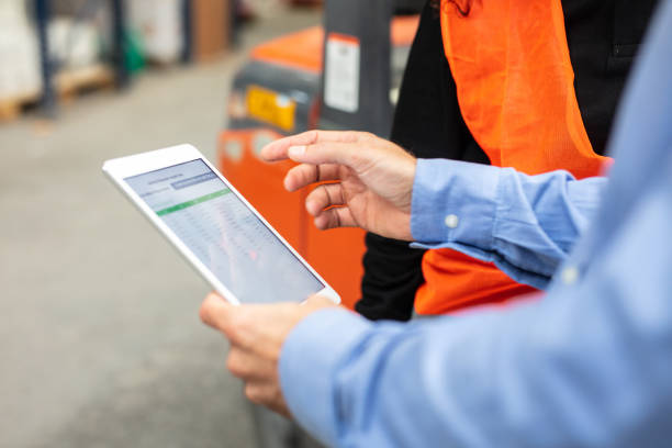 Foreman using digital tablet discussing dispatch plan with the worker Close-up of a foreman holding digital tablet discussing dispatch plan with the worker in warehouse. Cropped shot of supervisor with tablet pc talking with worker. forklift photos stock pictures, royalty-free photos & images