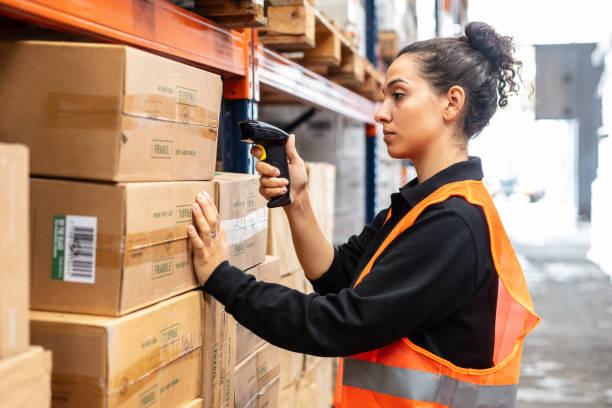 Woman scanning boxes with bar code scanner in warehouse shelf Young female worker scanning boxes with bar code scanner in warehouse shelf. Woman wearing reflective clothing working in modern warehouse. scanning activity stock pictures, royalty-free photos & images