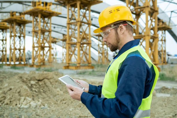 istock Serious engineer in workwear looking at sketch on tablet screen 1323169026