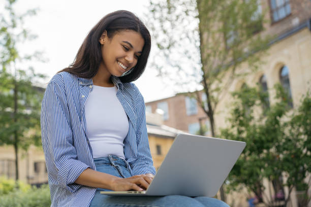 istock African American woman copywriter typing, working freelance project outdoors. Smiling student studying, distance learning, exam preparation, education concept 1323169927