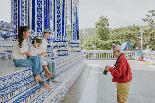 senior hipster photographer taking a photo for tourists at temple for spending time on weekend like a part time job