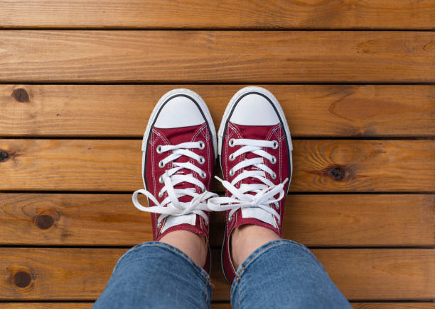 Women's feet in red sneakers on wooden pier floor with copy space Women's feet in red sneakers on wooden pier floor with copy space personal perspective standing stock pictures, royalty-free photos & images