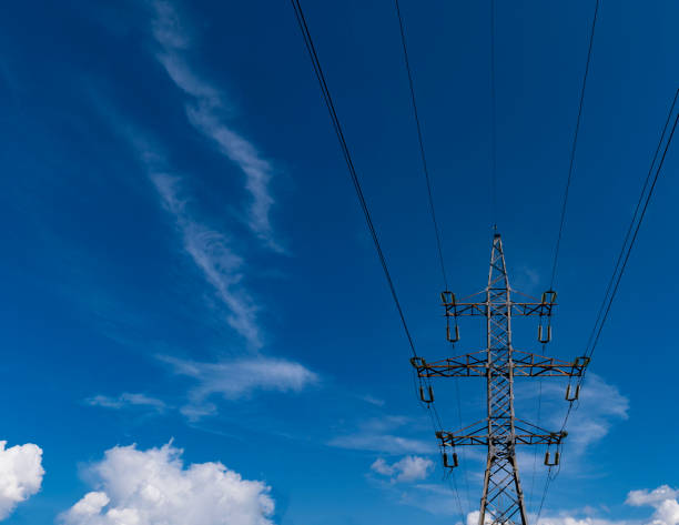 istock High-voltage pole against a blue sky with beautiful white clouds. Overhead power line wires. Bottom view 1323183923