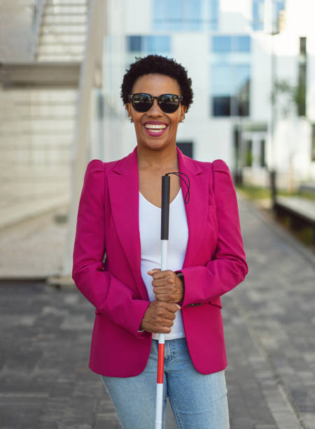 Portrait of a confident and charming mixed-race businesswoman, with visual impairment, standing in front of her corporate building while holding blind person cane
