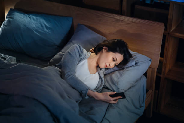 istock Smiling young Asian woman checking social media on smartphone while lying on bed before bedtime, spending a chilling night at cozy home 1323184843