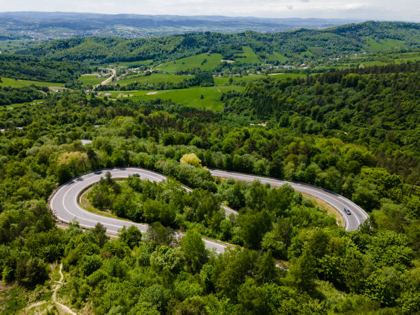 istock Curvy and Winding Road in Mountains. Drone View. Green Trees in forest 1323189499
