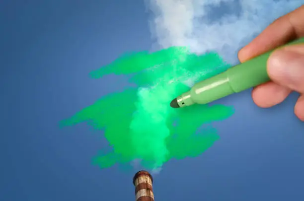 Photo of Man painting green pollution from a chimney