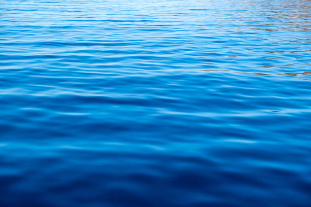 Sea water surface calm with small ripples, deep blue color background, some reflections. Tranquil seascape, Space