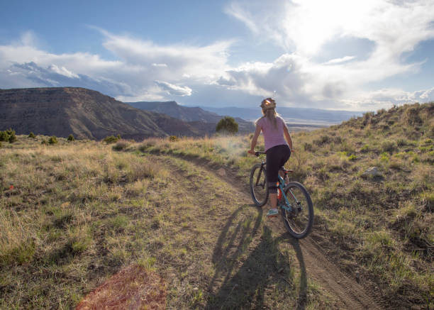 istock Female mountain biker follows trail along mountain ridge 1323199889