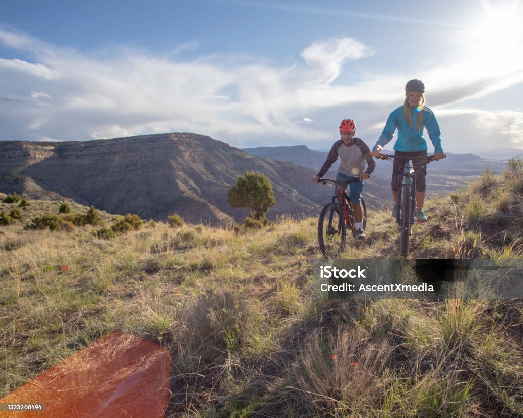 Mountain bikers follow trail along mountain ridge Desert landscape surrounding Colorado Stock Photo