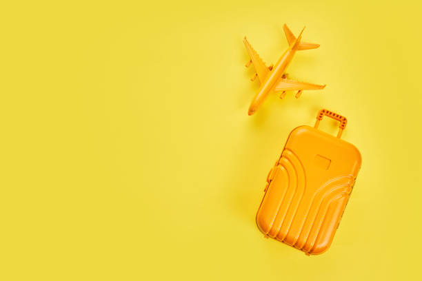 istock Flat lay yellow suitcase with plane on yellow background. Travel concept 1323201029