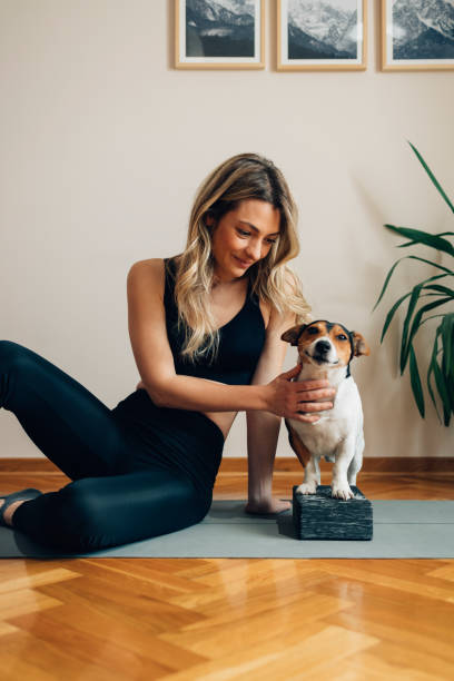 istock Happy Young Woman Sitting on the Exercise Mat with Her Dog 1323202049