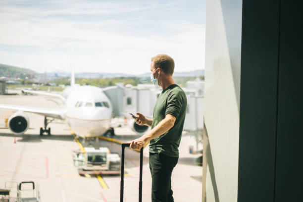 istock Young man wearing face mask walks through airport 1323206927