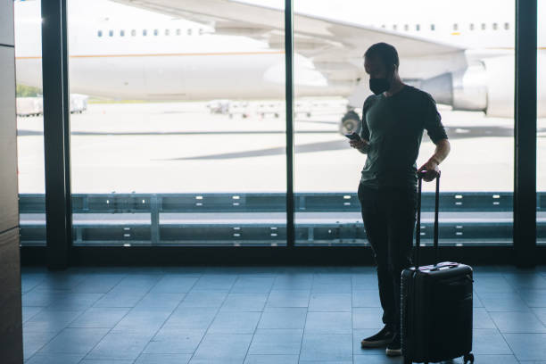 istock Young man wearing face mask walks through airport 1323207072