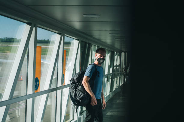 istock Young man wearing face mask walks through airport 1323207086