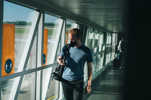 istock Young man wearing face mask walks through airport 1323207089