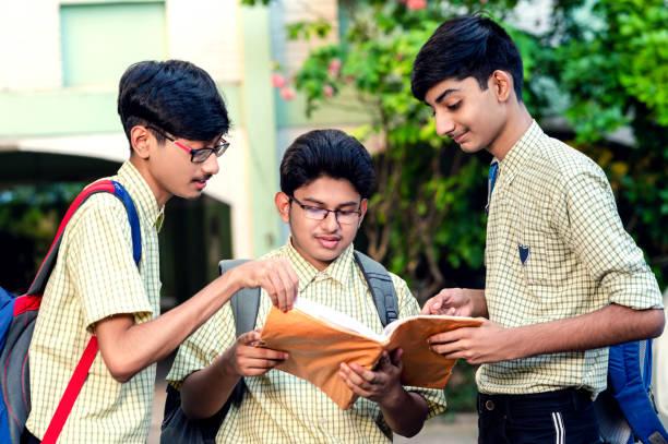 istock A group of three young school students discussing on a book outside the school building. 1323207844