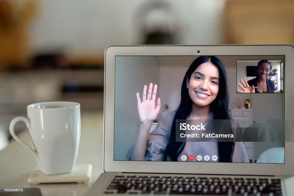 Virtual medical appointment An African American 27 year old video calls a Middle Eastern 56 year old coworker in her kitchen. Psychotherapy Stock Photo