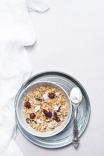 Granola with chia seeds, coconut, dry berries and yogurt in bowls on grey background, copy space. Concept of healthy breakfast menu