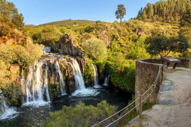 Poço da Broca waterfall in Serra da Estrela Natural Park, Barriosa, municipality of Seia in Portugal, with a viewpoint in the foreground, at the end of a spring day. This type of cascade results from human intervention. Many years ago, with the help of drills, they changed the course of the river to use land for agriculture. These waterfalls, several meters high, create wells, hence the name Poço da Broca. schist stock pictures, royalty-free photos & images