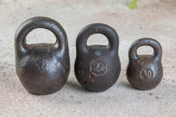 Three antique iron weights for scales on concrete background.