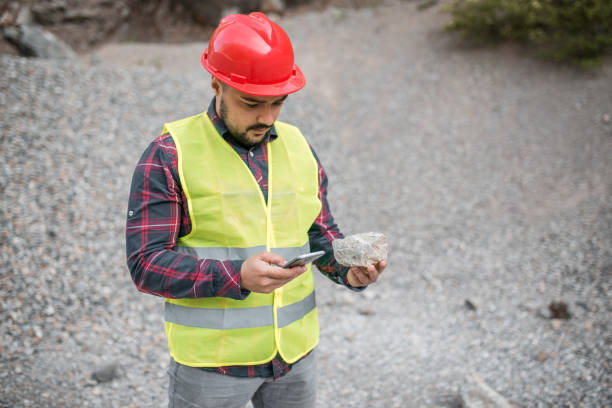 istock Bearded worker in uniform holding stone and mobile phone 1323228947
