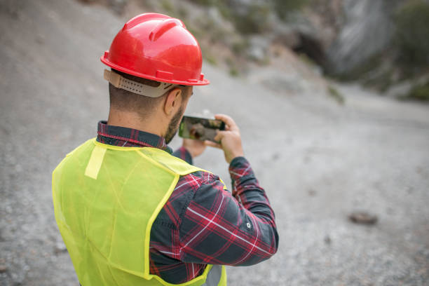 trabajador toma una foto de piedra que encontró trabajando en la construcción de carreteras - trabajador de construcción fotos fotografías e imágenes de stock