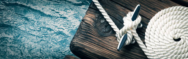 Coiled Boat Rope Secured To Cleat Close-up Of Coiled Boat Rope Secured To Cleat On Wooden Dock moored stock pictures, royalty-free photos & images