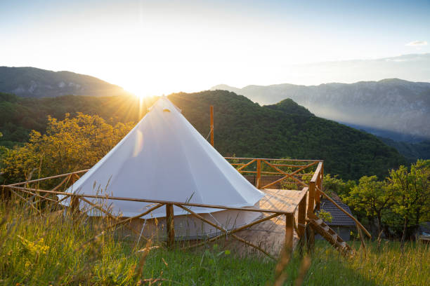 glamping tent in the morning sunlight with mountain range panorama beautiful panorama of glamping house tent in the morning sun light on wooden deck with fence and foggy mountain range scenery in the background glamping photos stock pictures, royalty-free photos & images