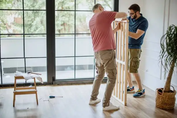 Senior father and mid adult son, installing bed frame together on father’s day